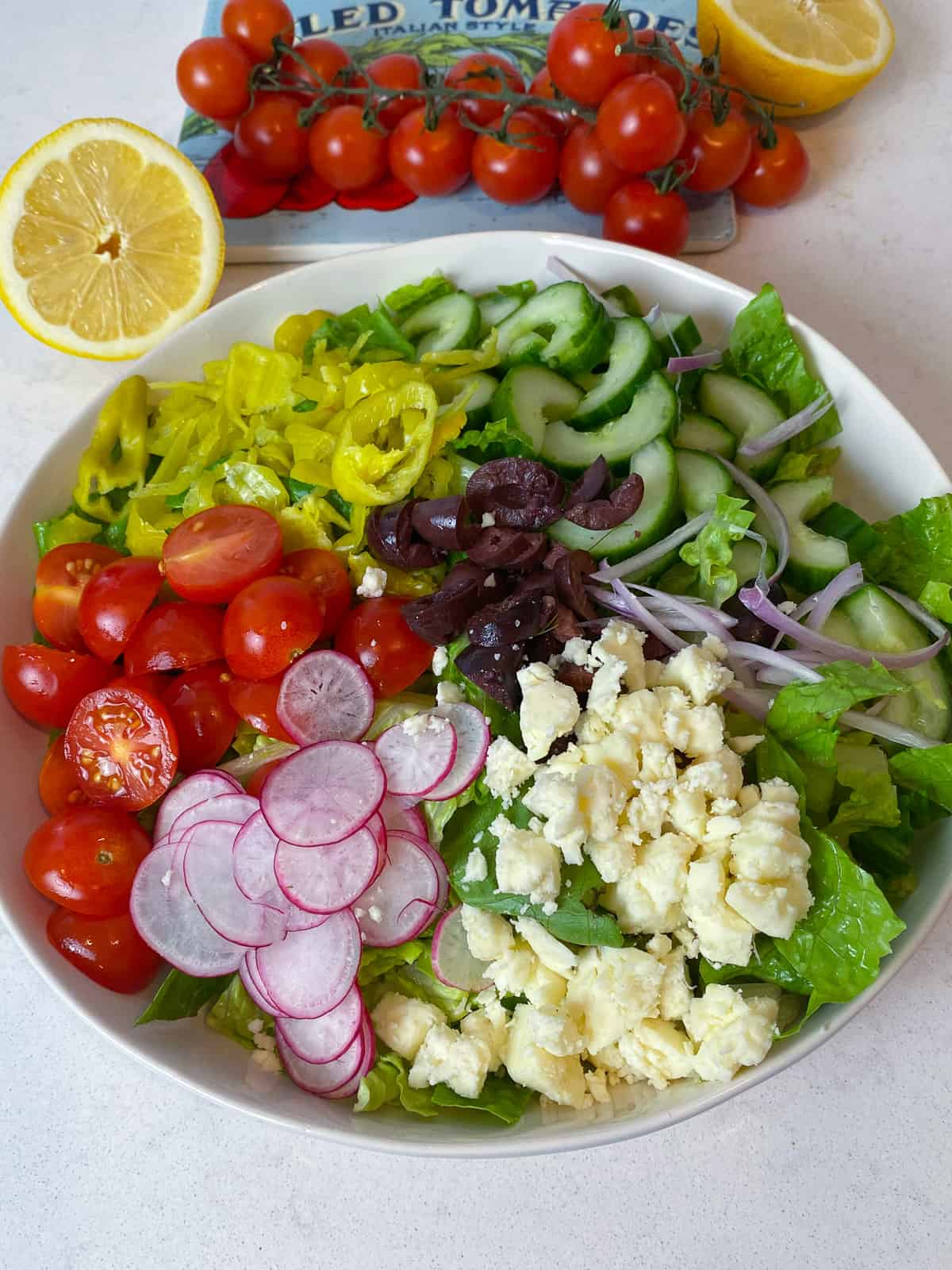 Layer all the Greek salad ingredients in a wide bowl.