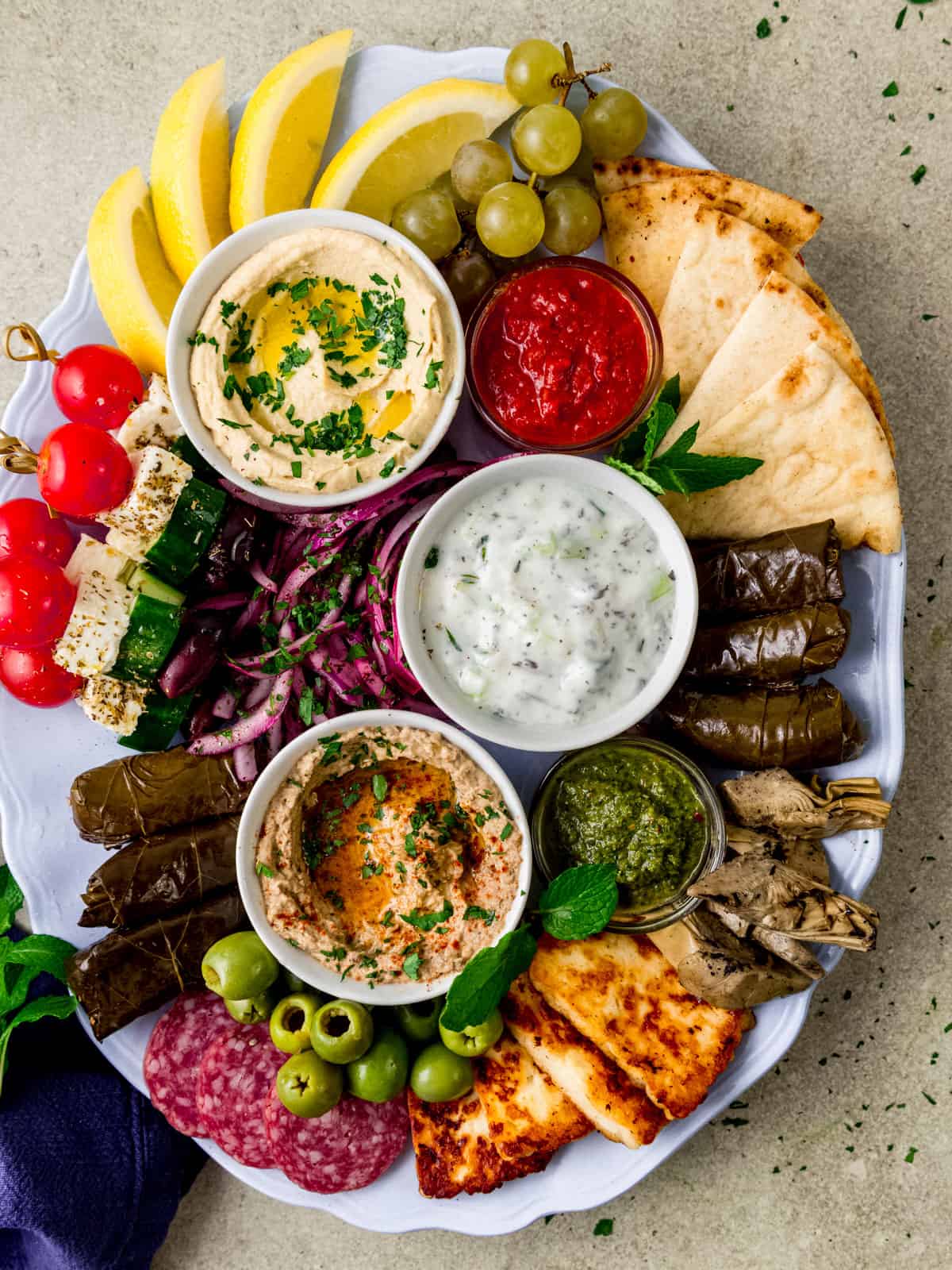 Loaded Mediterranean charcuterie board with salad skewers, stuffed grape leaves and hummus.