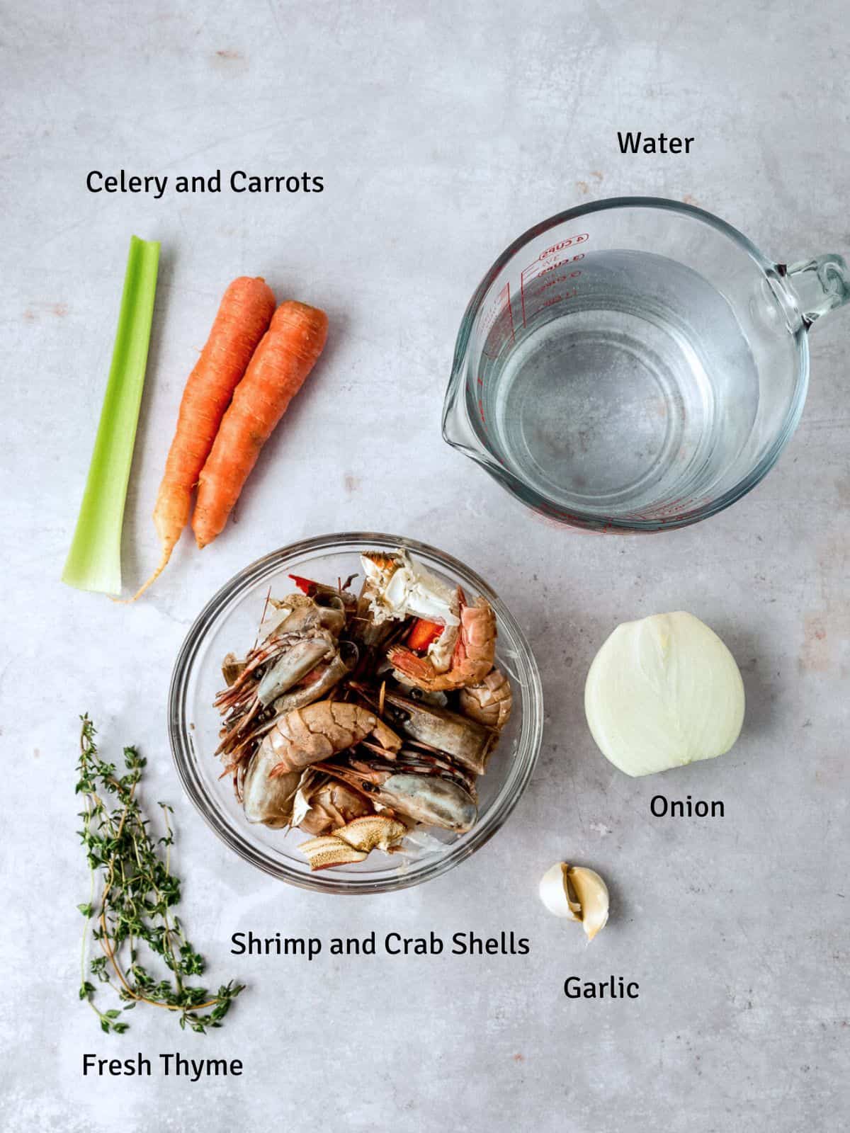 Ingredients for seafood stock, including shrimp shells, carrots, garlic and fresh herbs.
