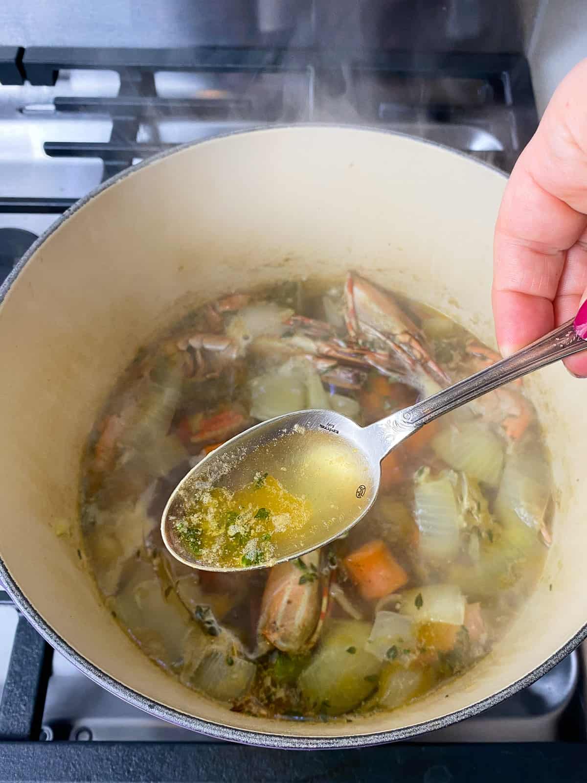 Use a spoon to skim away any impurities and foam that float to the top of the seafood stock.