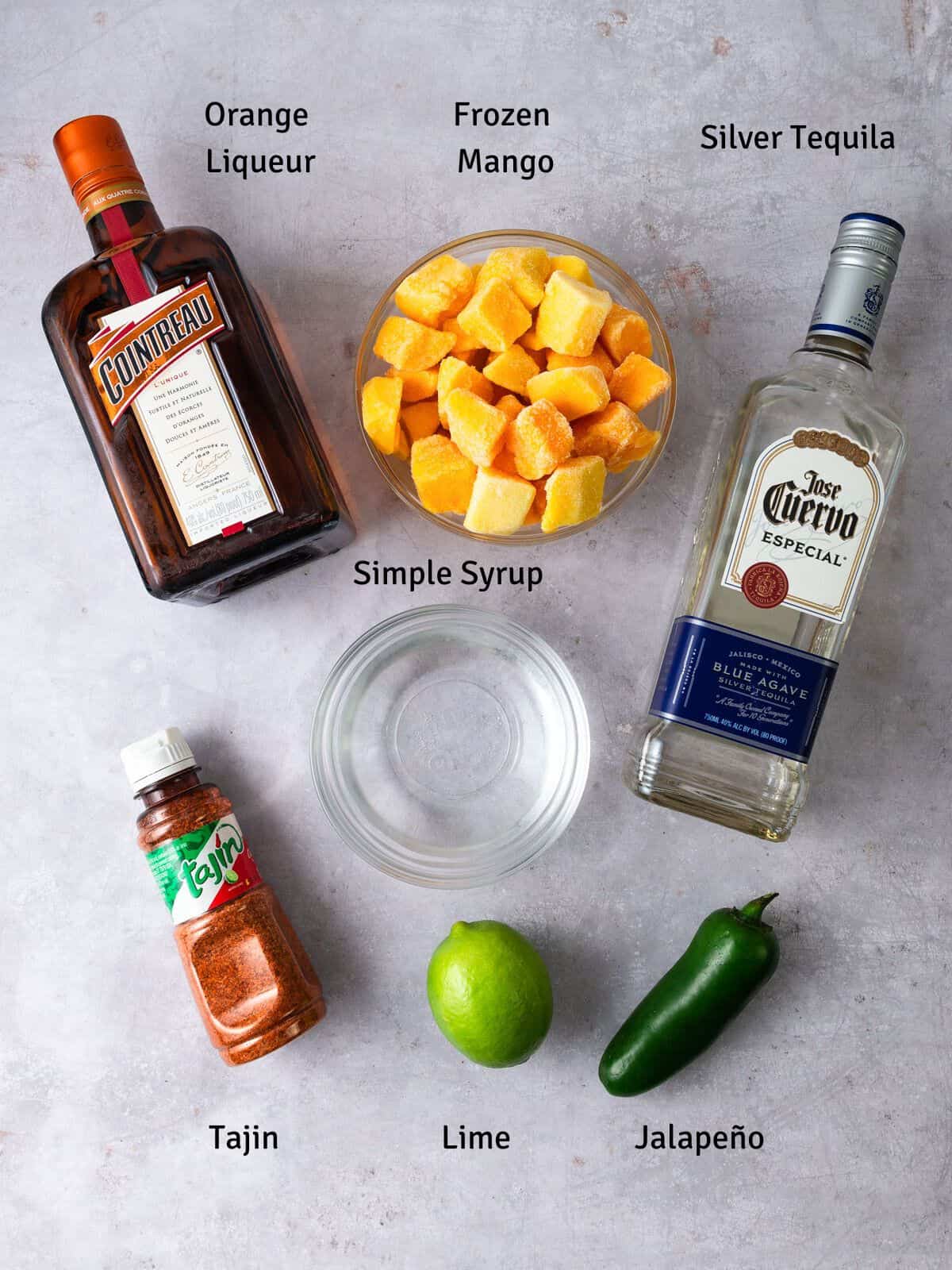 Ingredients for spicy mango margarita, including silver tequila, lime and tajin.
