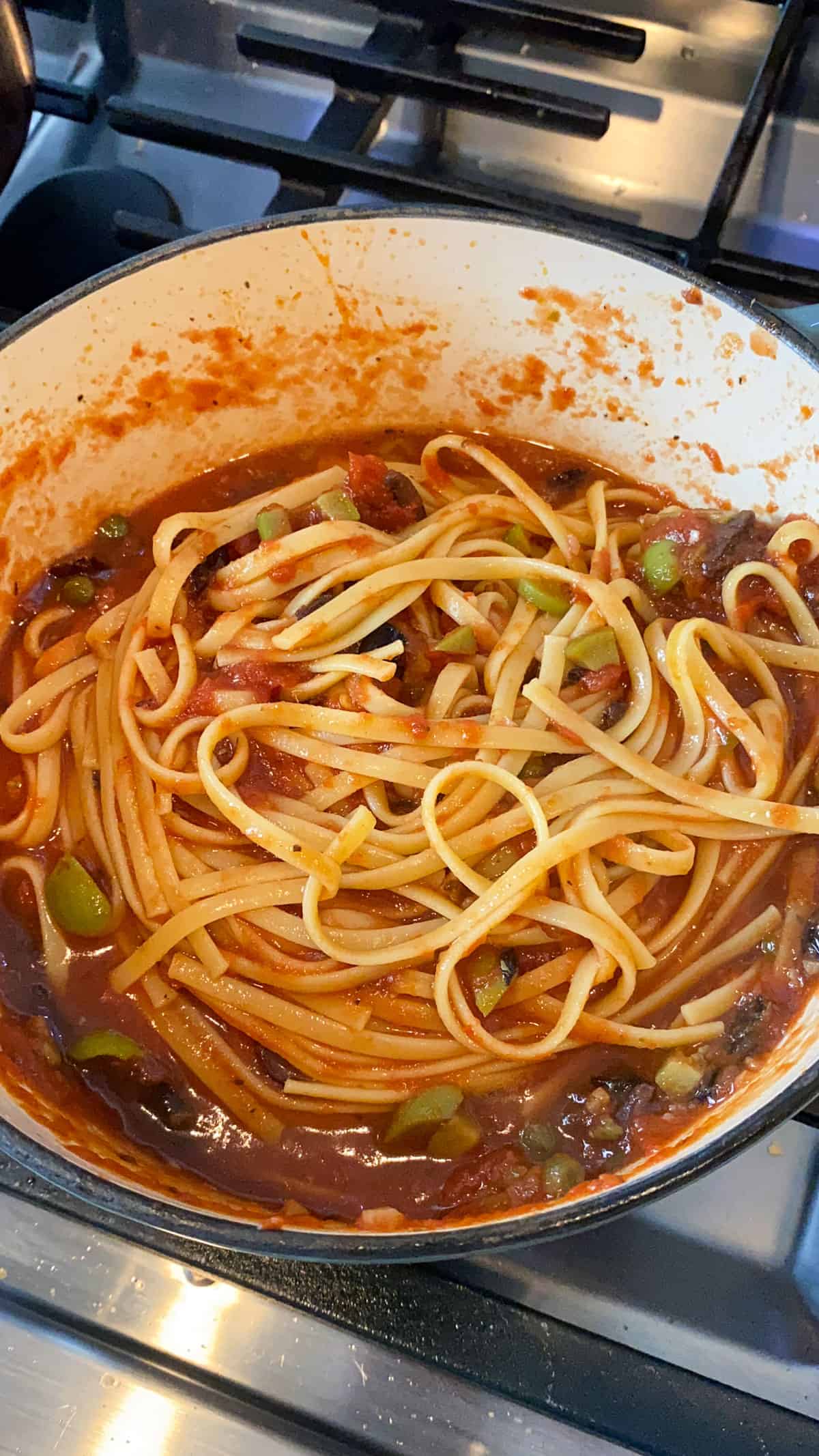 Toss the cooked pasta with the puttanesca sauce so all of the sauce evenly coats the noodles.