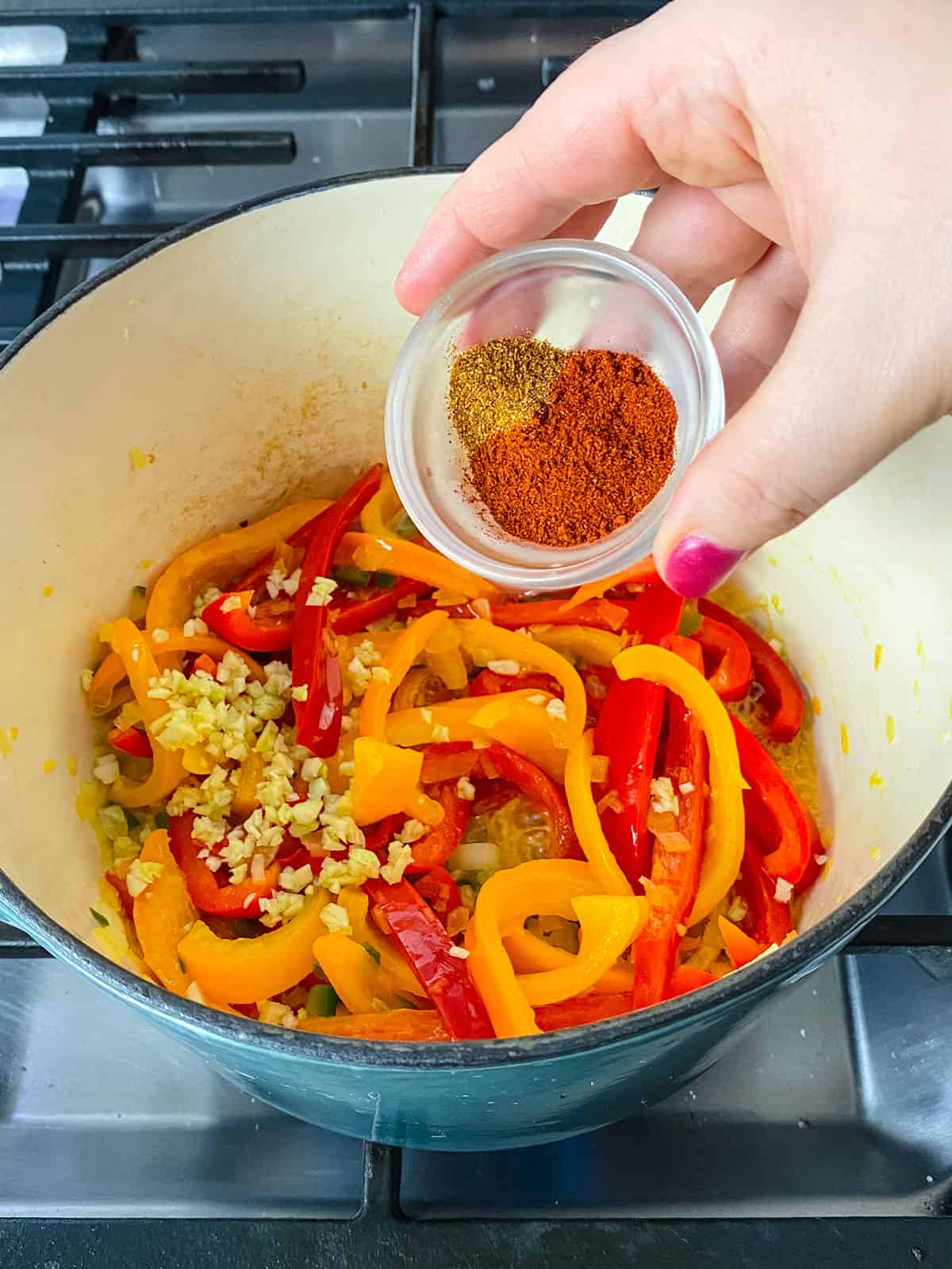 Add the chopped garlic, paprika and cayenne to the sautéed bell peppers and stir together.