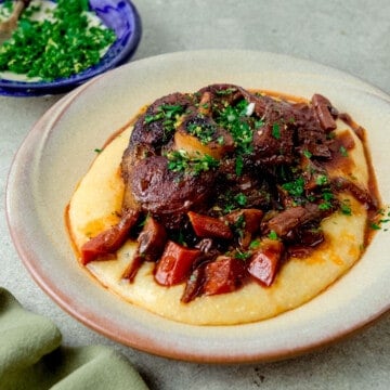 Classic osso buco recipe served over creamy polenta and garnished with herb gremolata.