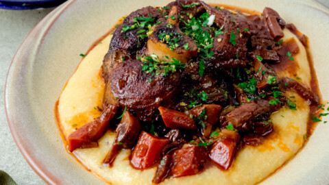 Classic osso buco recipe served over creamy polenta and garnished with herb gremolata.