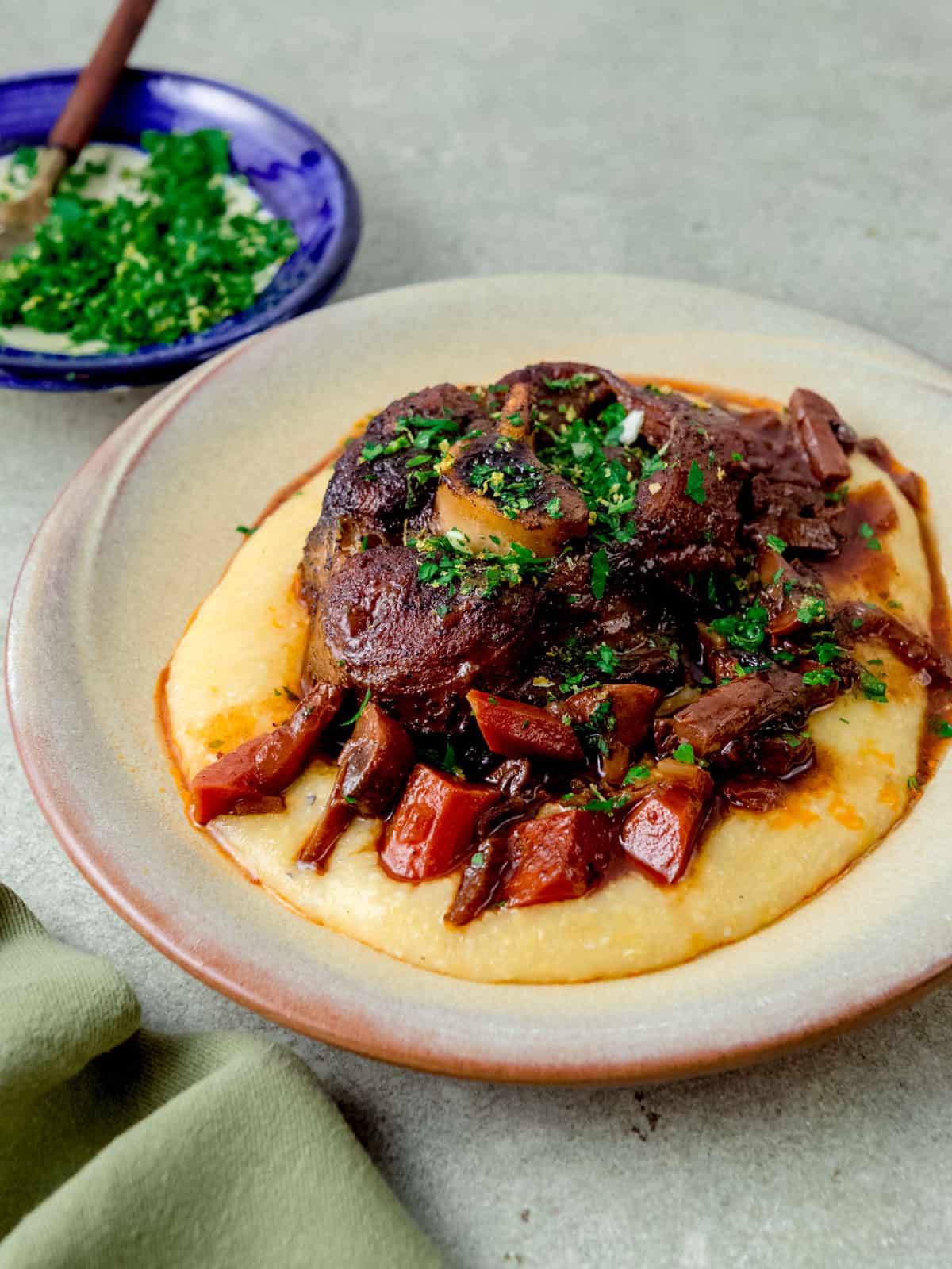 Osso buco served over polenta and topped with gremolata.