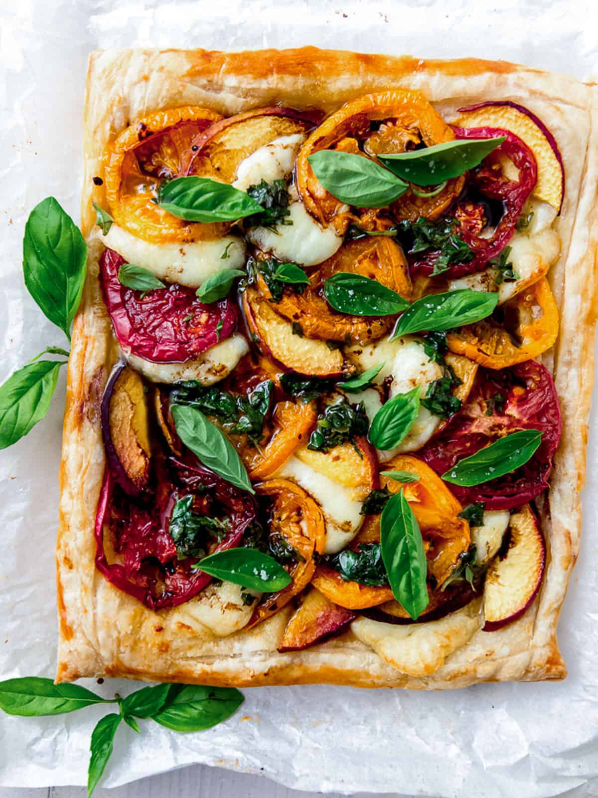 Peach caprese tart with puff pastry and basil.