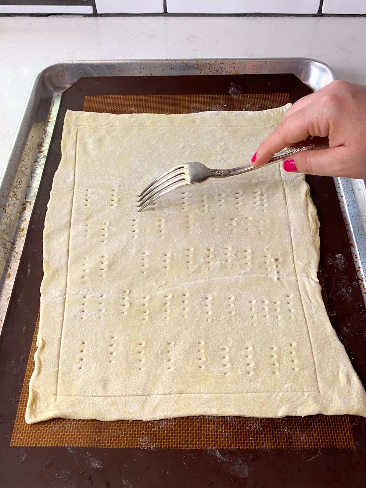 Score a border around the puff pastry and use a fork to dot holes in the center of the pastry.