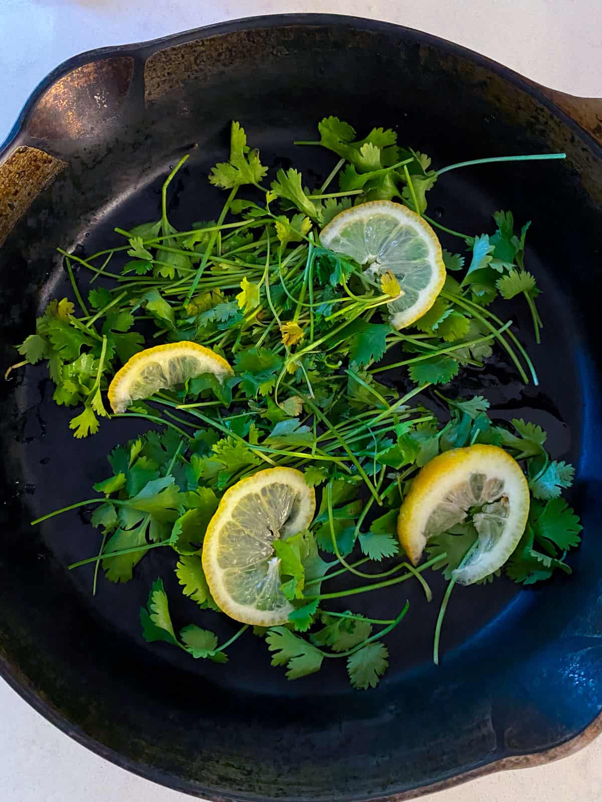 Lay fresh herbs and a few lemon slices on the bottom of the baking dish or cast iron.