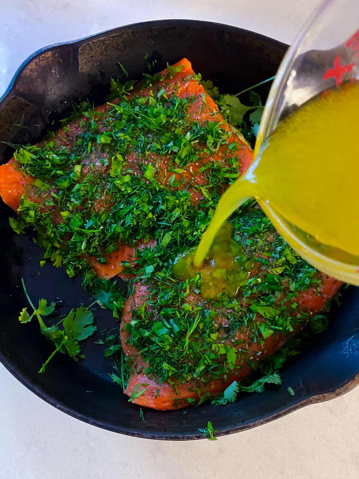 Pour the white wine and olive oil mixture around the herb salmon and pour some on top as well.