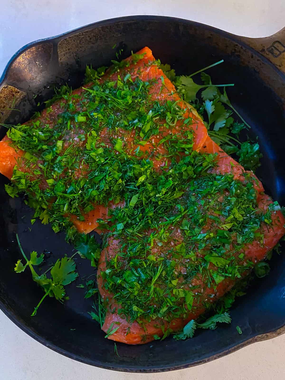 Press the fresh herbs onto the salmon filet so the herbs stick to the fish easily.
