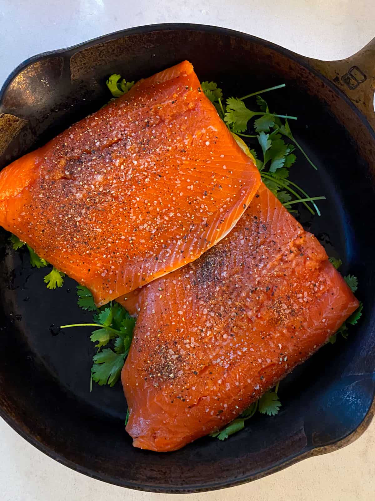 Place the salmon filets on top of the fresh herbs ands season with salt and pepper.