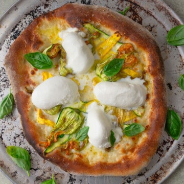 Squash blossom pizza with creamy burrata cheese and fresh basil.