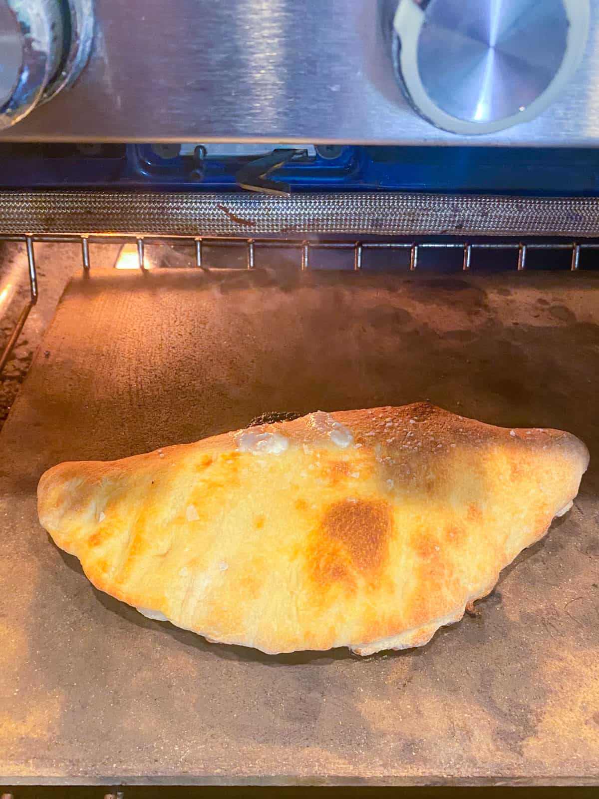 Bake the cheese calzone on a pizza stone in a hot oven until the outside is golden brown.