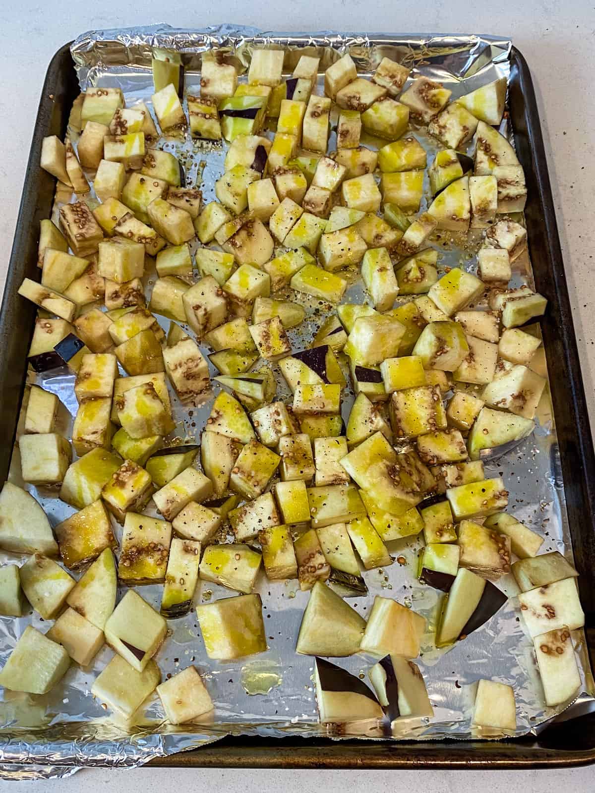 Add the cubed eggplant to a baking sheet and drizzle with olive oil.