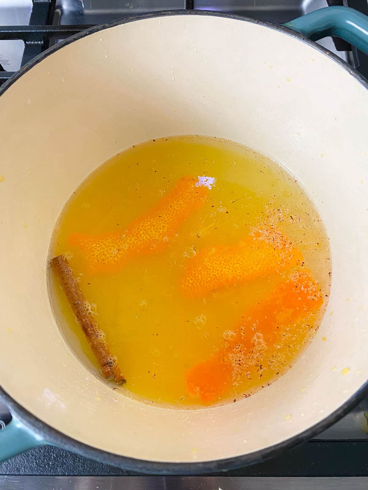 Add all of the pear poaching liquid to a pot, including the cinnamon stick, nutmeg, orange peels, sugar and white wine.