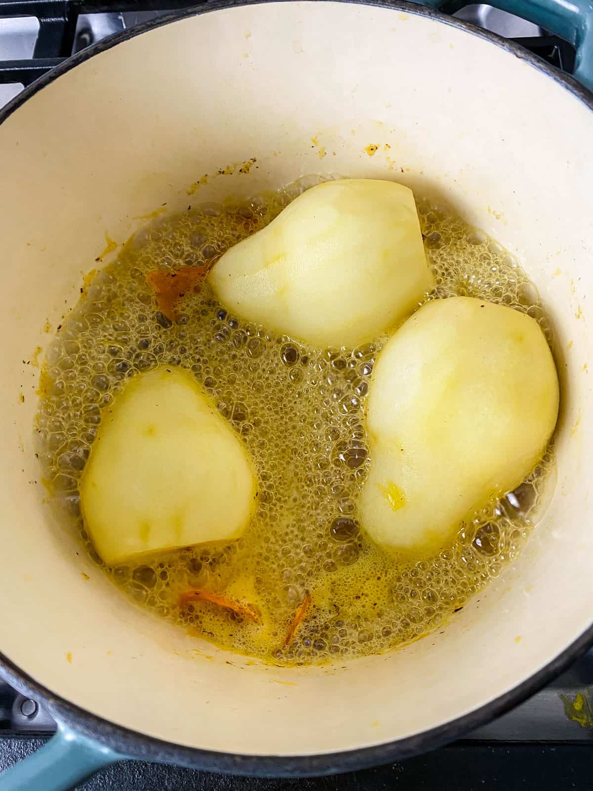 Simmer the peeled pears in the wine poaching liquid until tender and sauce has reduced.