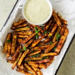 Baked zaatar fries are garnished with fresh thyme and served with a creamy herb tahini sauce.