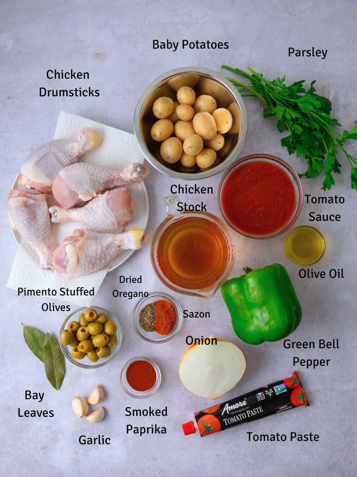 Ingredients for Spanish chicken stew, including bone in chicken parts, baby potatoes, olives, spices and bell pepper.