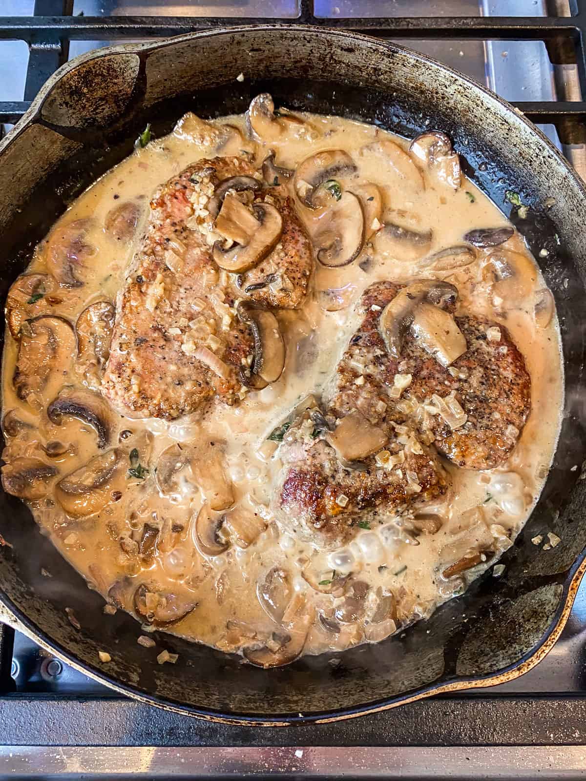 Add the seared steaks back into the creamy marsala sauce and baste the steaks with the sauce.