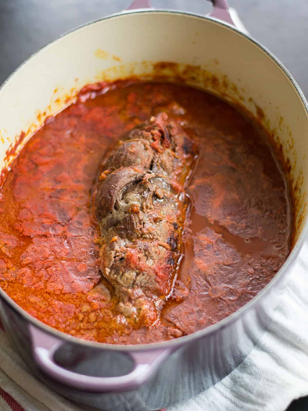 Seared braciole is simmered in a rich tomato sauce until tender.
