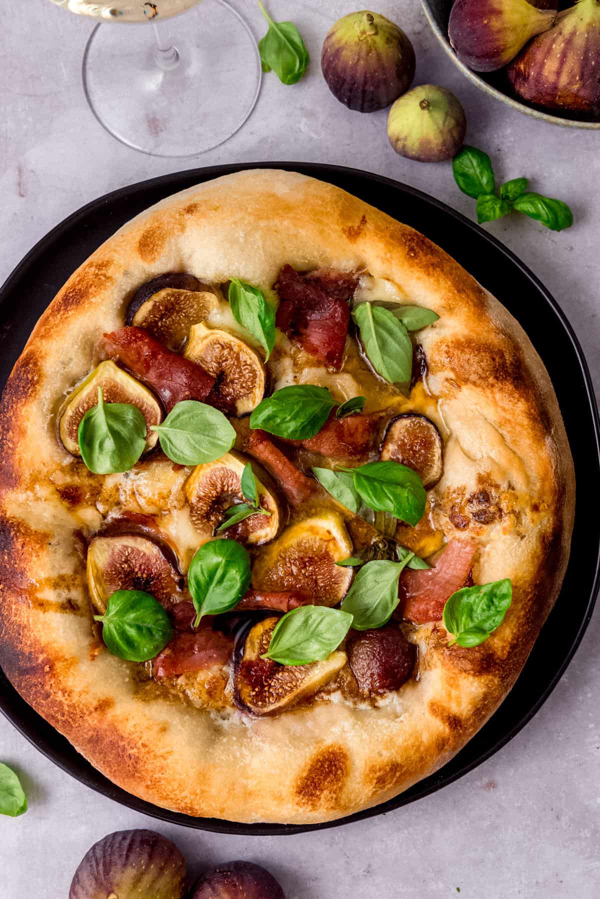 Prosciutto and fig pizza topped with a drizzle of balsamic and fresh basil leaves.