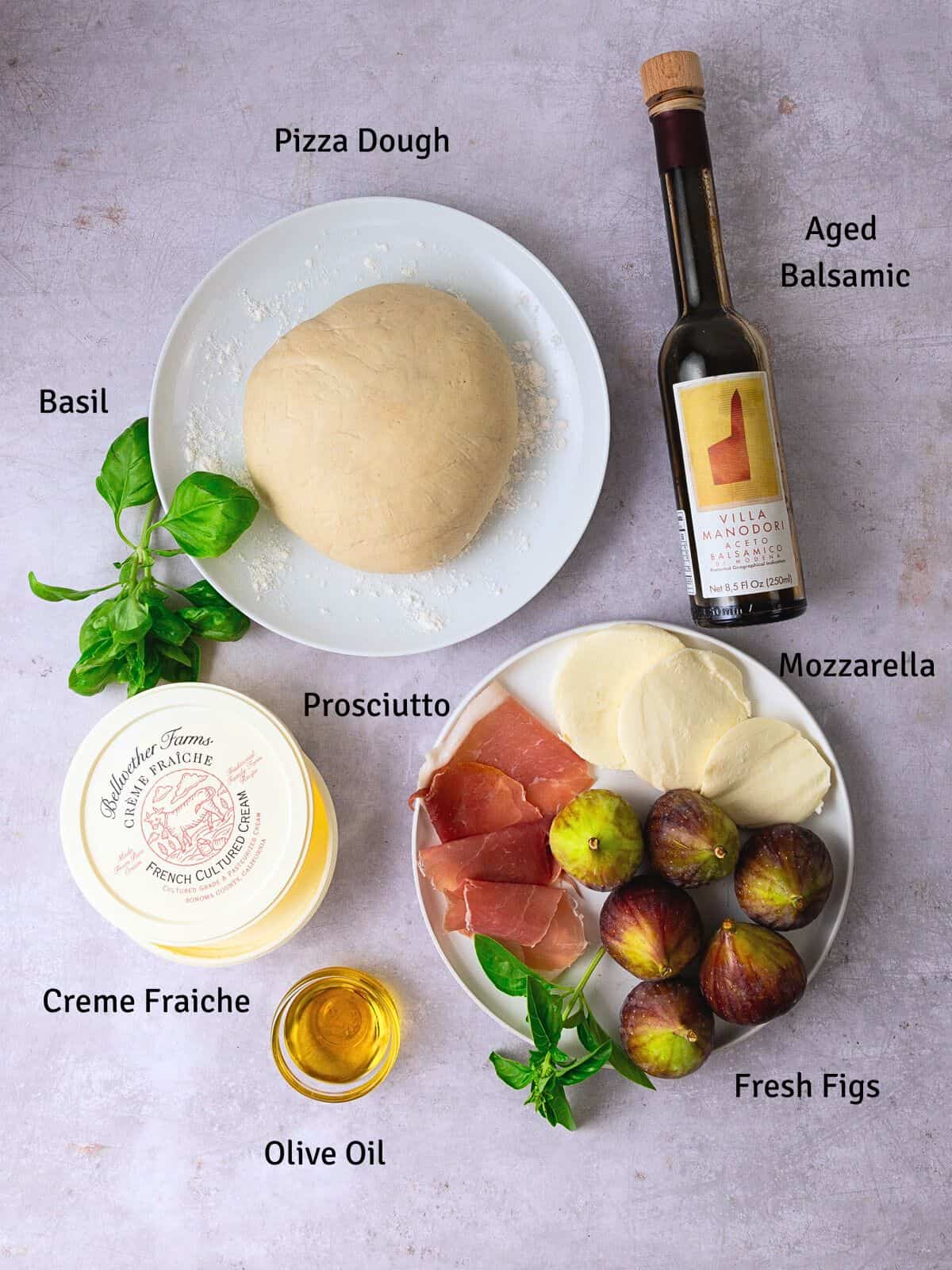 Ingredients for fig and prosciutto pizza, including creme fraiche, mozzarella, basil and aged balsamic,