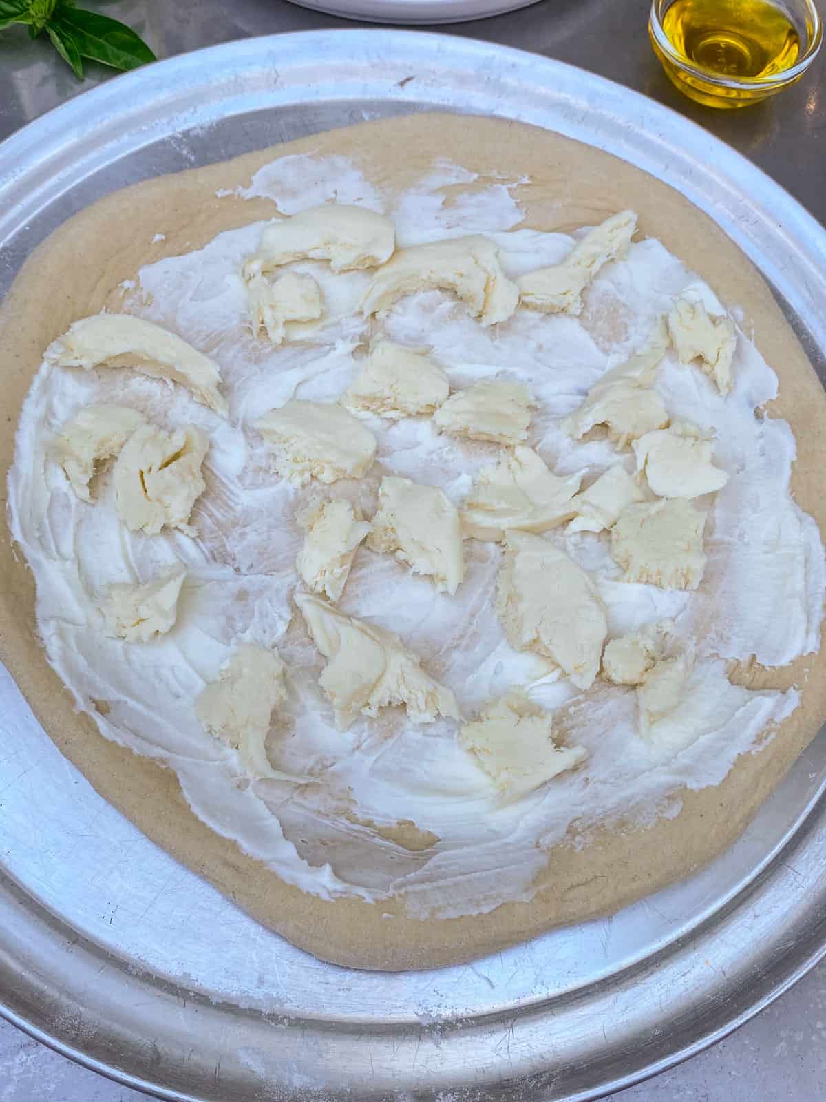 Spread a thin layer of creme fraiche onto the pizza dough and layer mozzarella cheese.