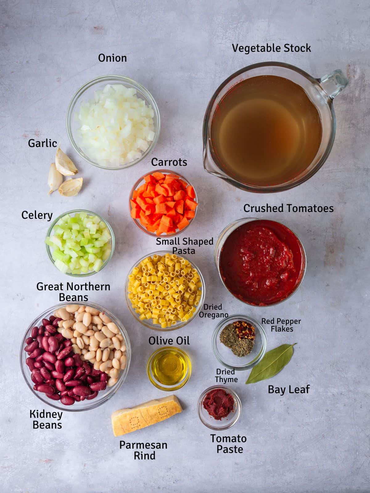 Ingredients for vegetarian pasta fagioli, including beans, pasta, parmesan rind, vegetables and spices.