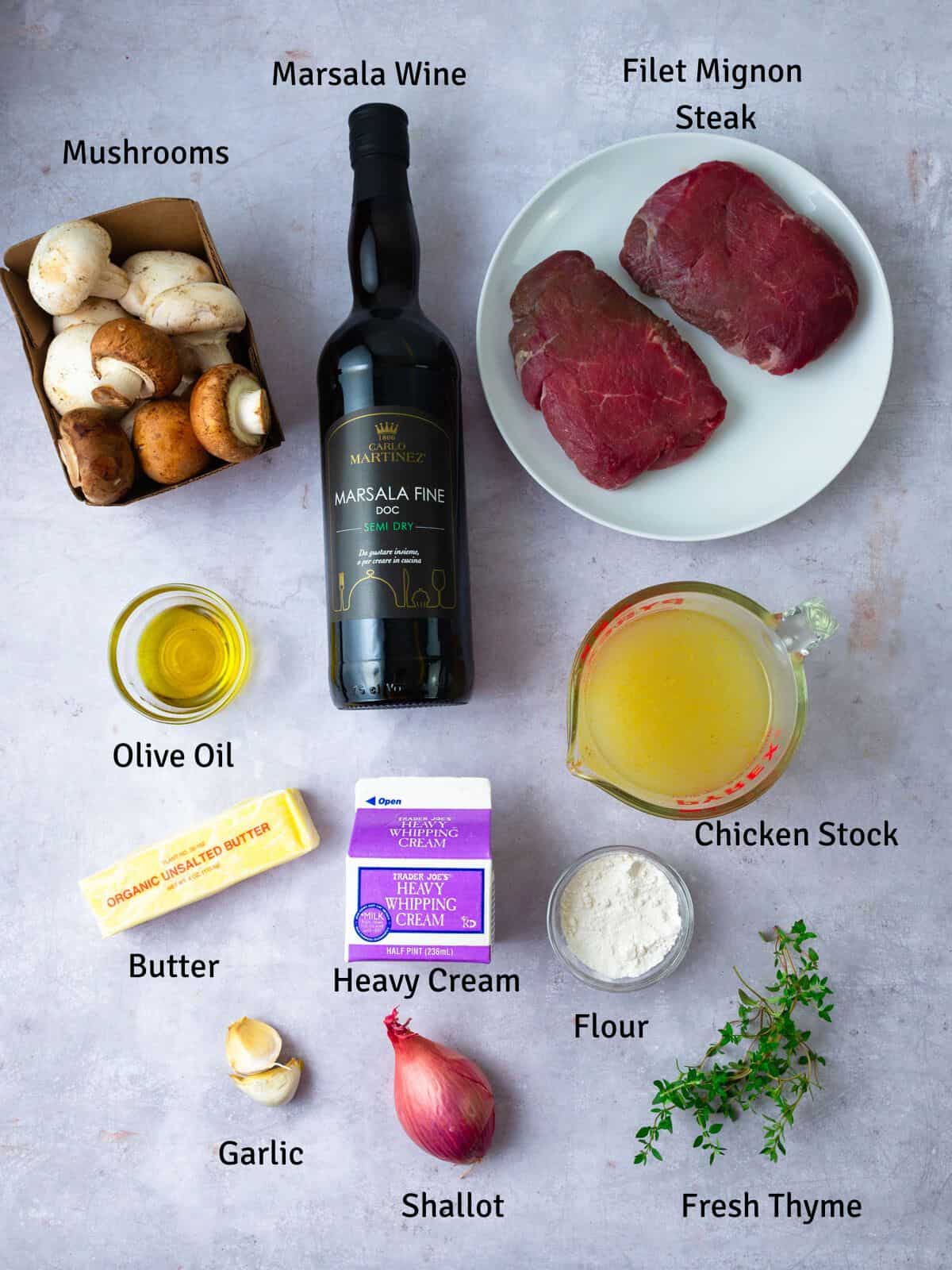 Ingredients for steak marsala, including filet mignon, button mushrooms, marsala wine, shallots, heavy cream, chicken stock and herbs.