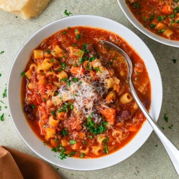 Vegetarian pasta fagioli recipe with pasta and beans and topped with grated Parmesan cheese and fresh herbs.