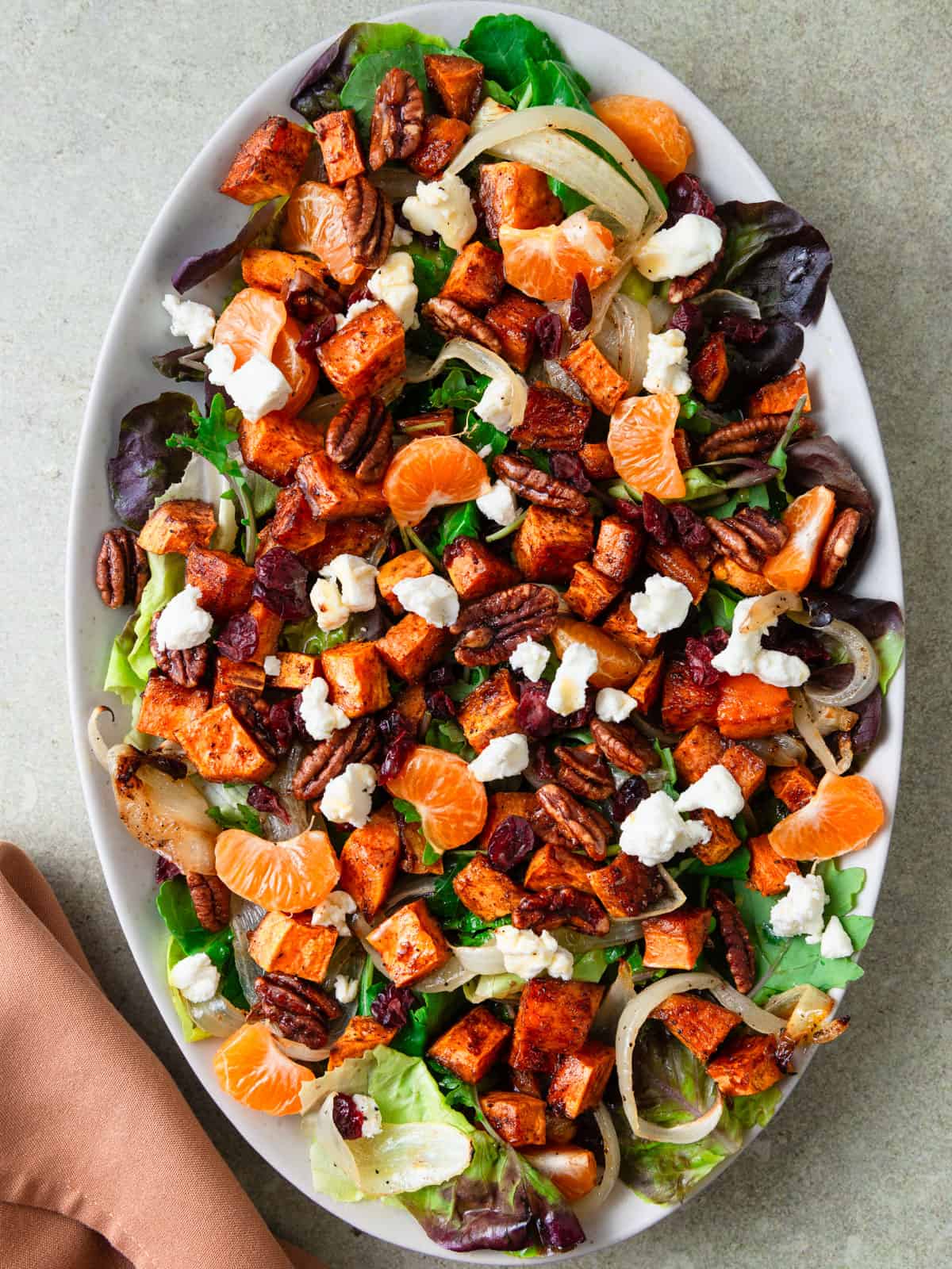 Roasted sweet potato salad is layered with citrus, roasted onions, creamy goat cheese and dried cranberries.