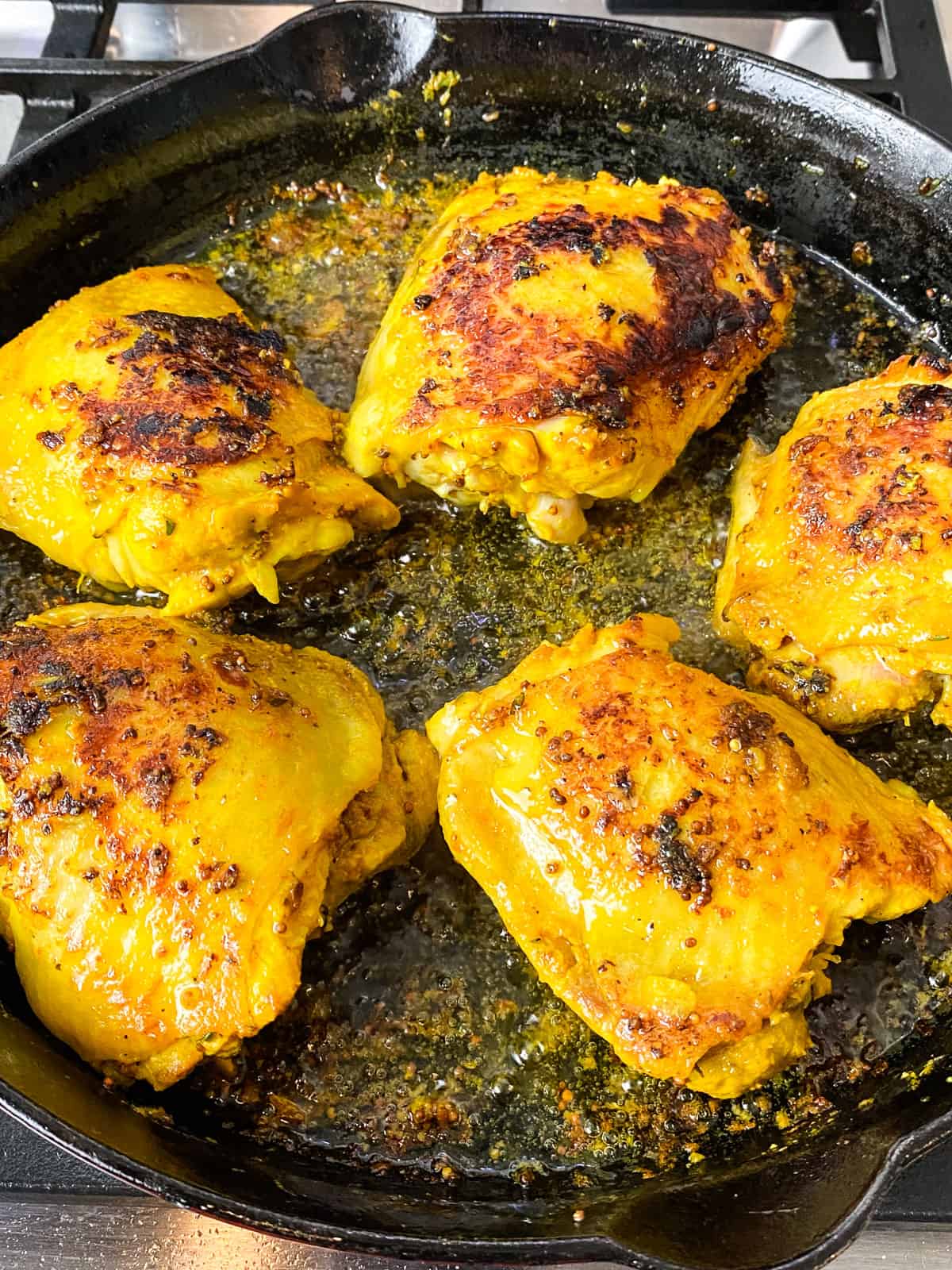 Sear the turmeric chicken thighs in a hot cast iron skillet until deeply charred.