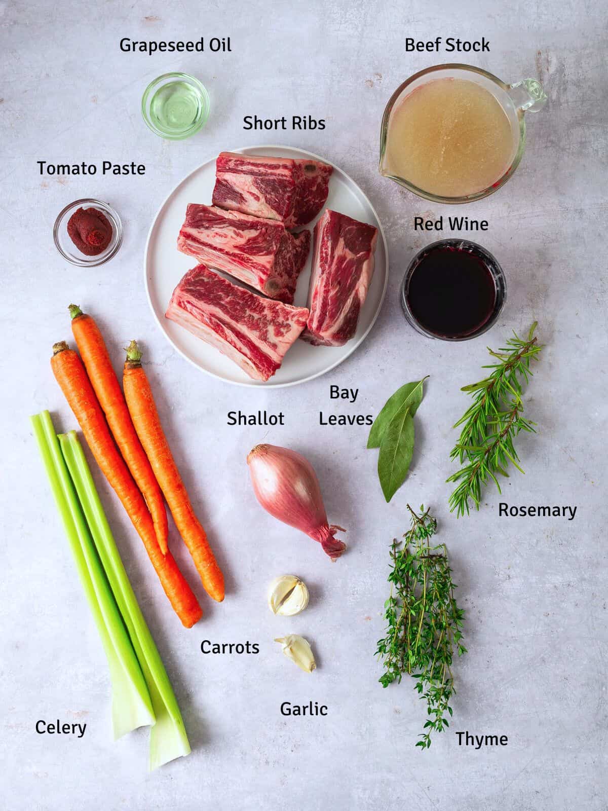 Ingredients for red wine braised short ribs, including carrot, celery shallot, garlic and fresh herbs.