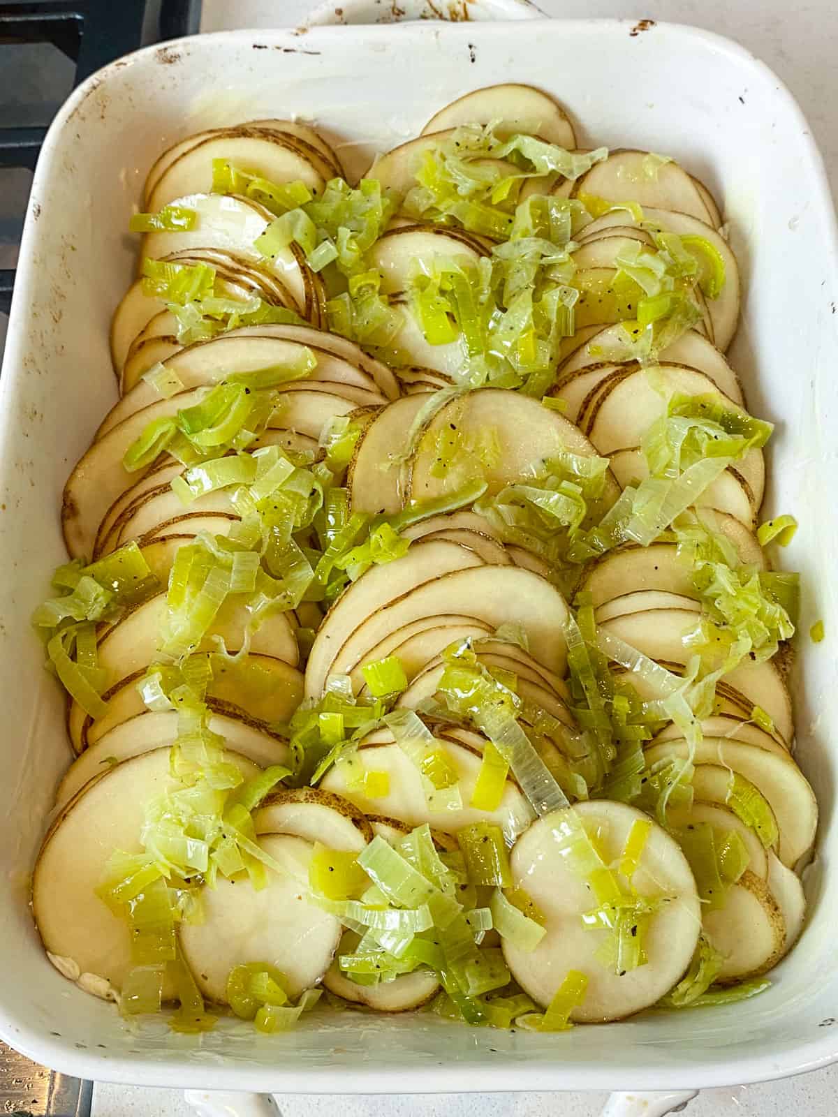 Add the rest of the sautéed leeks on top of the thinly sliced potatoes.