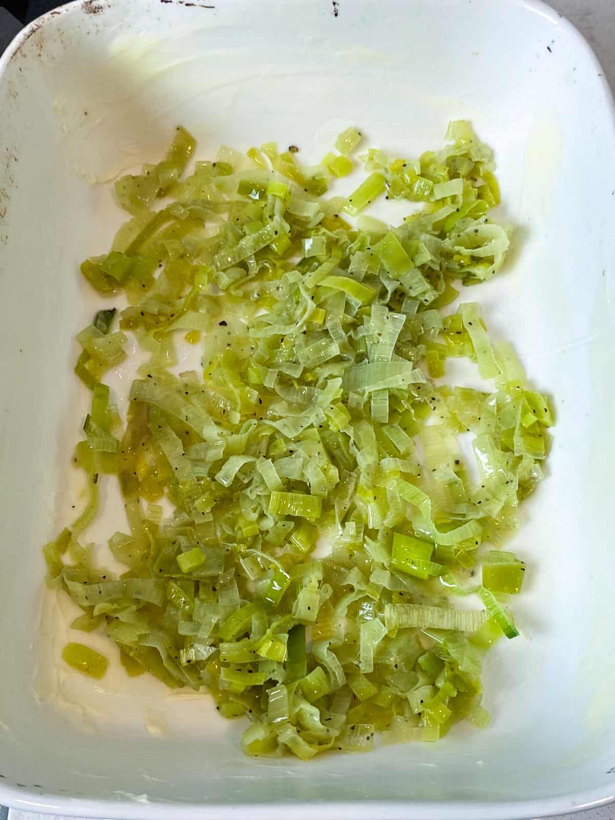 Add half of the sautéed leeks to the bottom of a buttered baking dish.