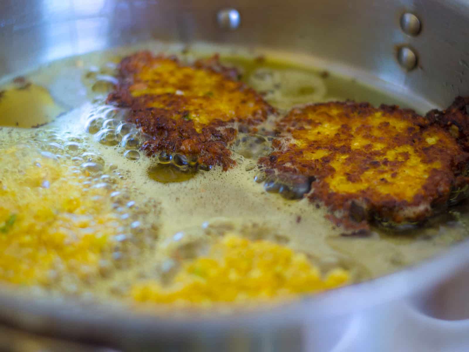Fry the cauliflower latkes until golden brown on both sides.