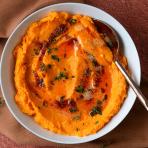 Savory mashed sweet potatoes recipe garnished with smoked paprika butter and fresh thyme.