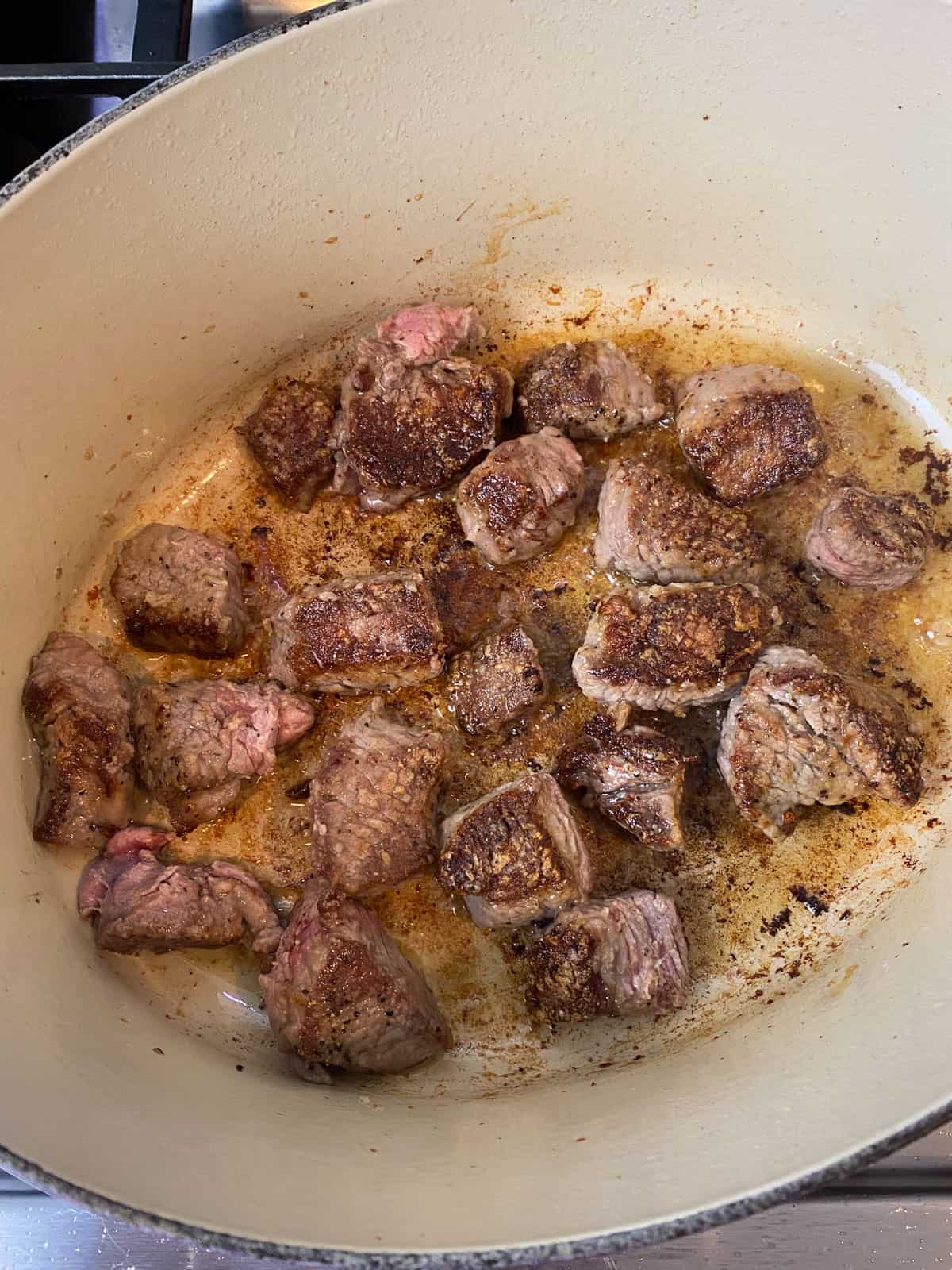 Sear the beef cubes in the bacon fat until deeply caramelized.