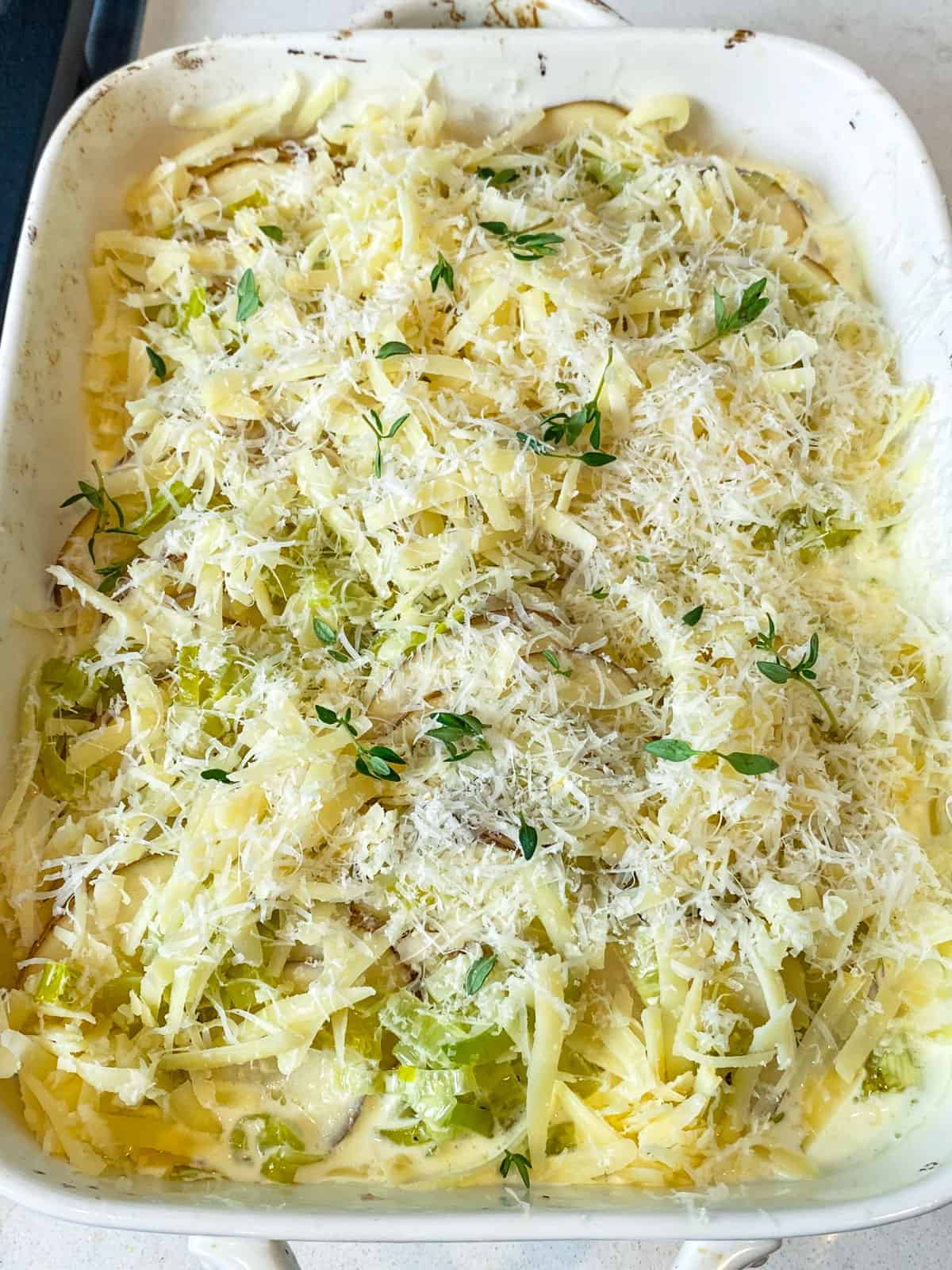 Top the potato leek gratin with shredded gouda cheese and grated Parmesan cheese.