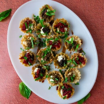Cheese stuffed phyllo cups with pesto, sun-dried tomatoes and basil.