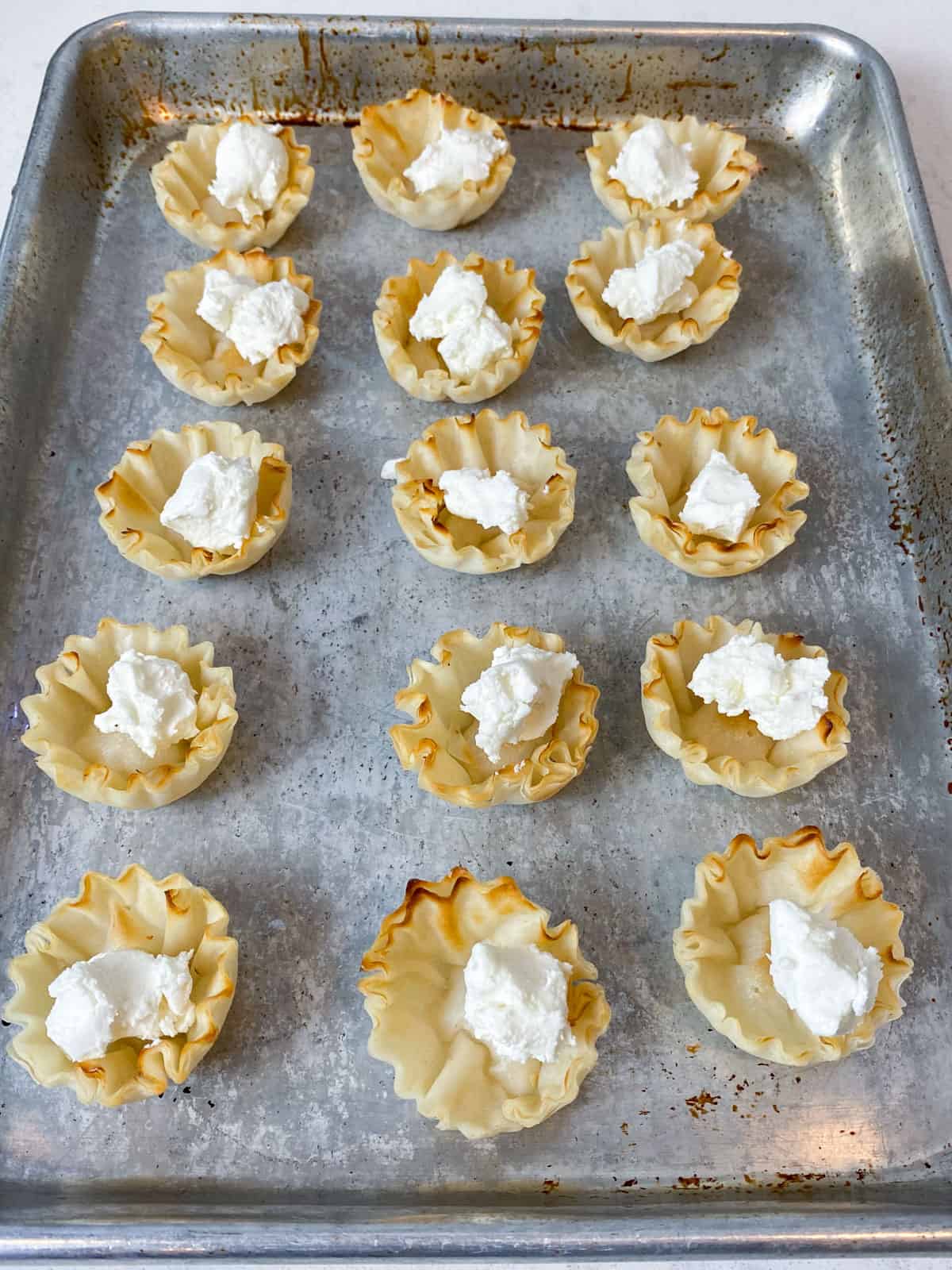Add crumbled goat cheese to phyllo cups.