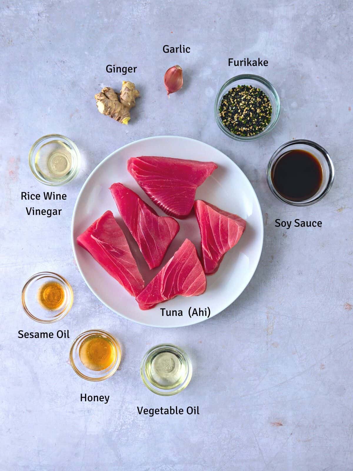 Ingredients to make seared ahi with furikake, including raw tuna, soy sauce, ginger and garlic.