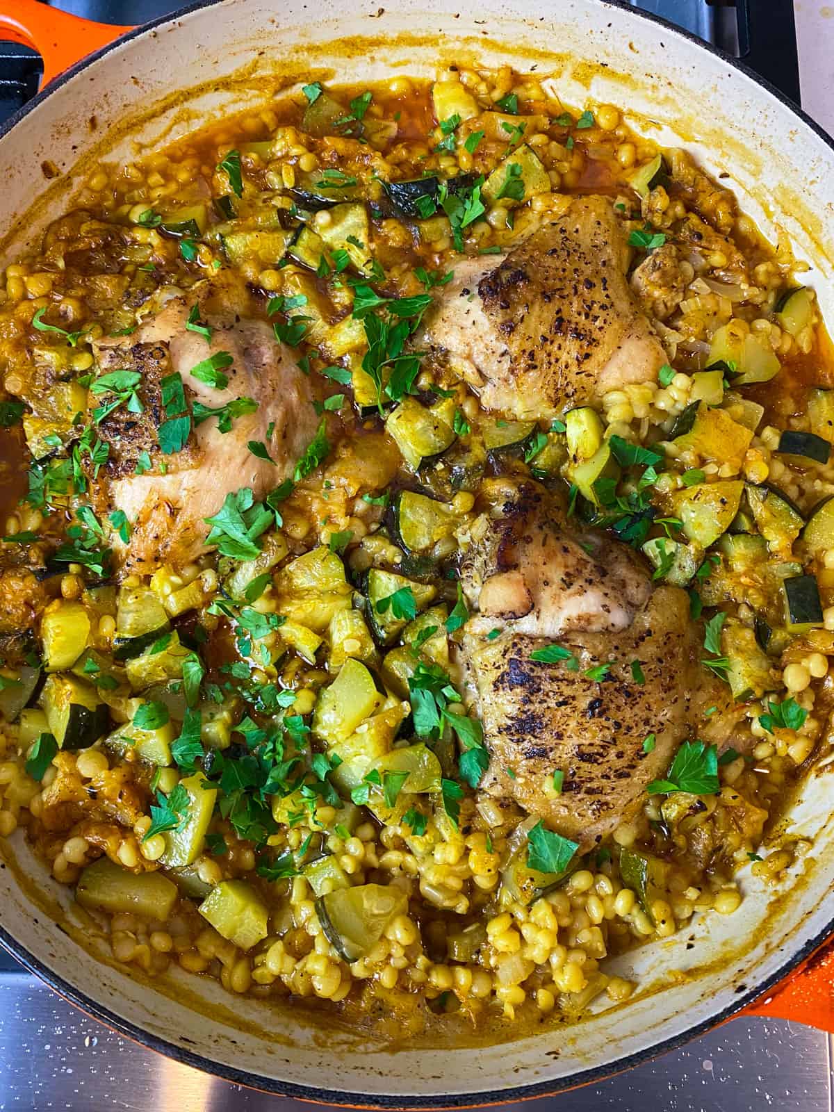 Bake the Israeli couscous and chicken until cooked through, then garnish with fresh parsley.