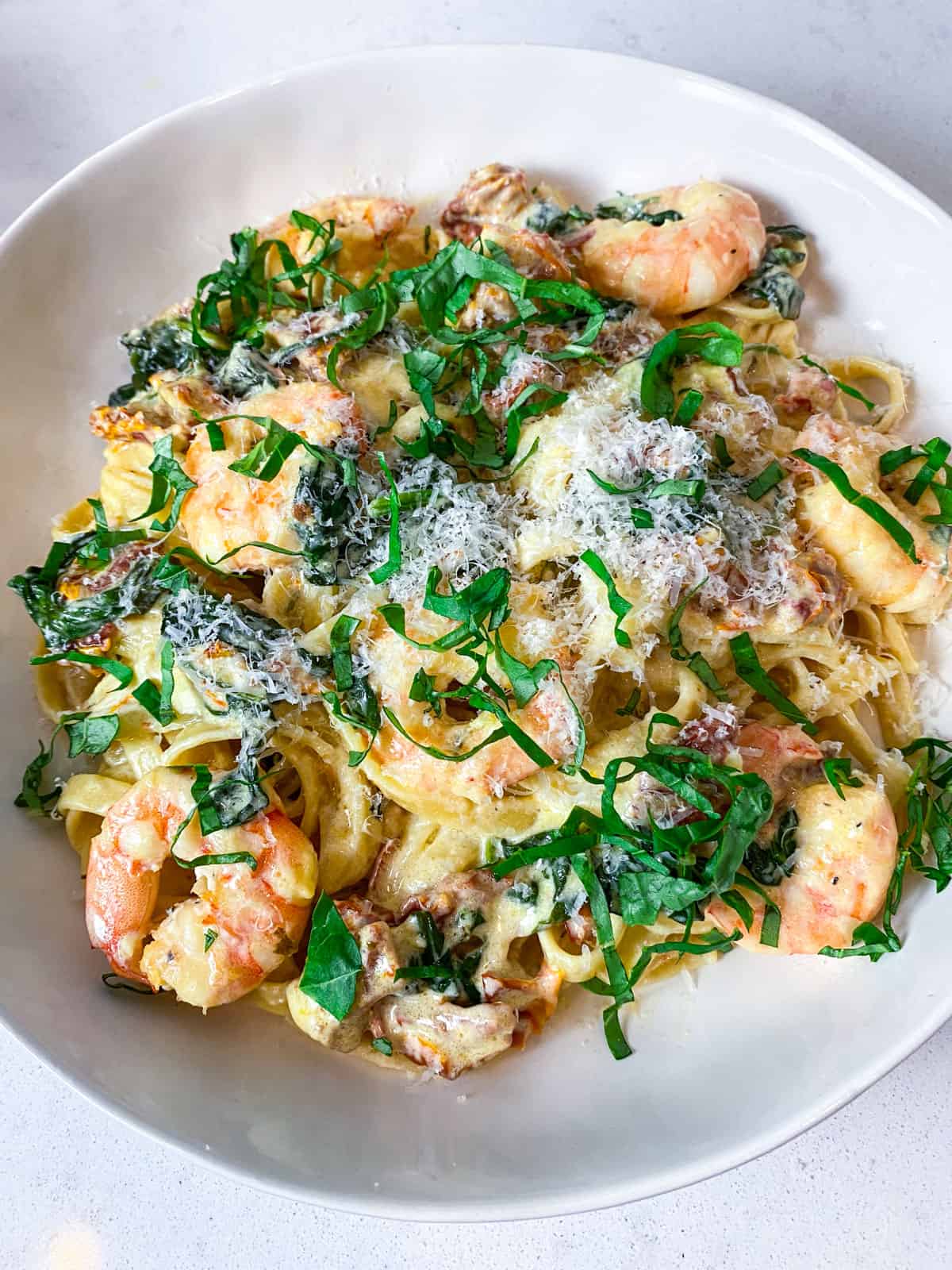 Garnish the tuscan shrimp pasta with fresh basil.