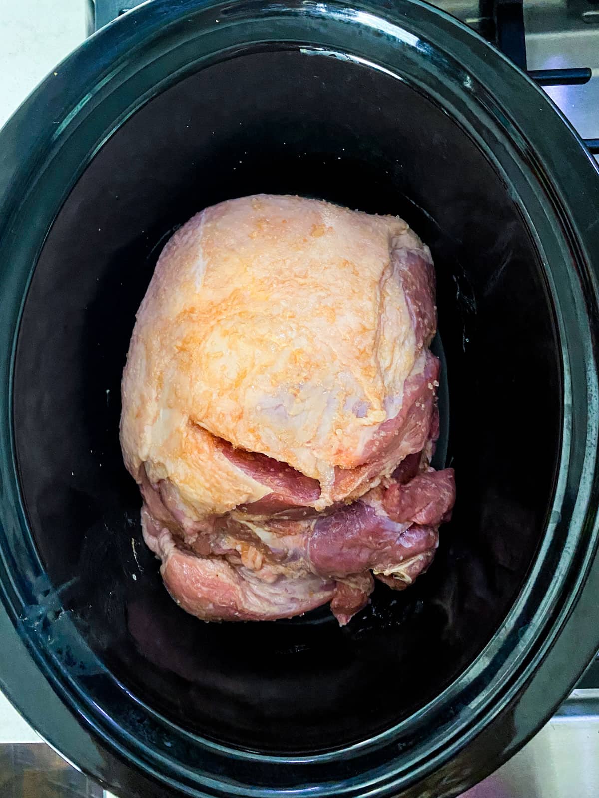 Place the salted pork shoulder in the slow cooker.