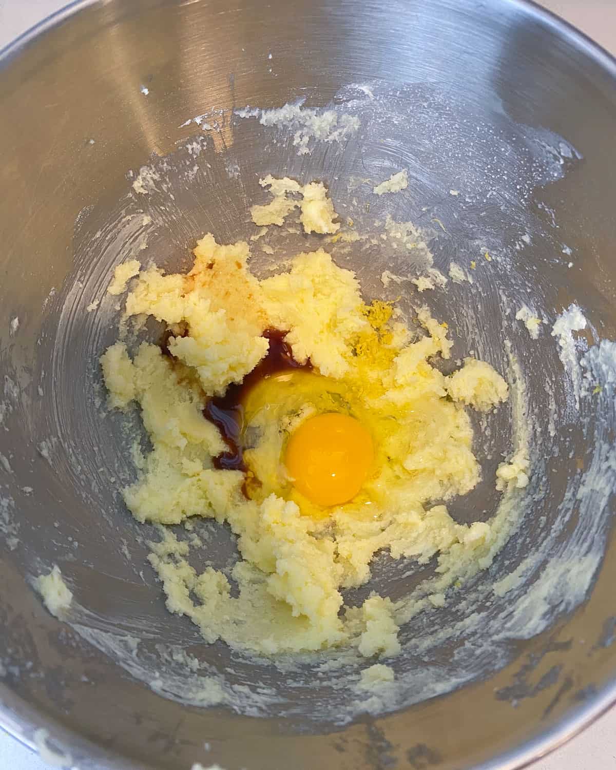 Add an egg, the vanilla extract and fresh lemon zest to the creamed butter mixture and continue mixing until well combined.