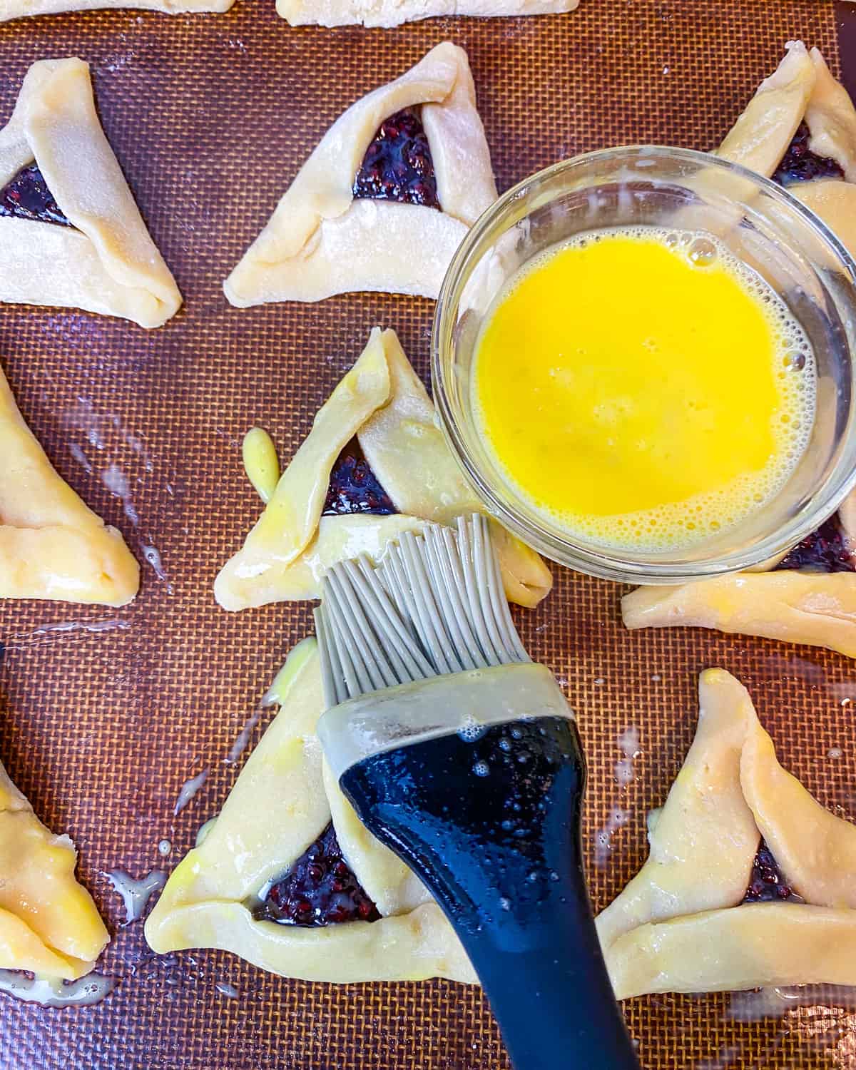 Brush the hamantaschen cookies with egg wash before baking.