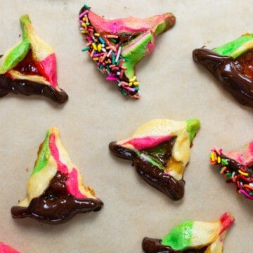 Rainbow hamantaschen cookies filled with apricot jam and dipped in chocolate.