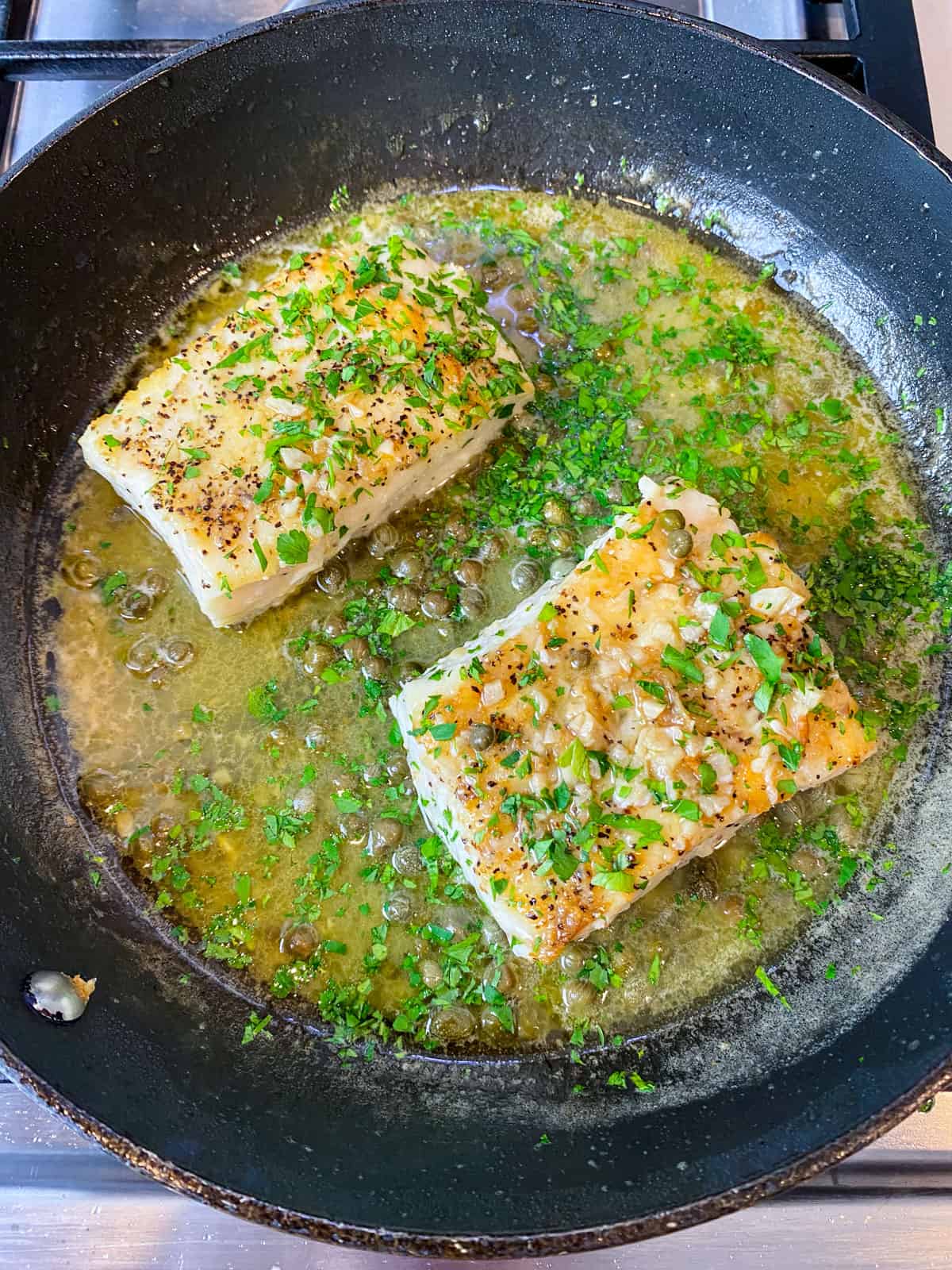 Add capers and chopped parsley to the halibut piccata.